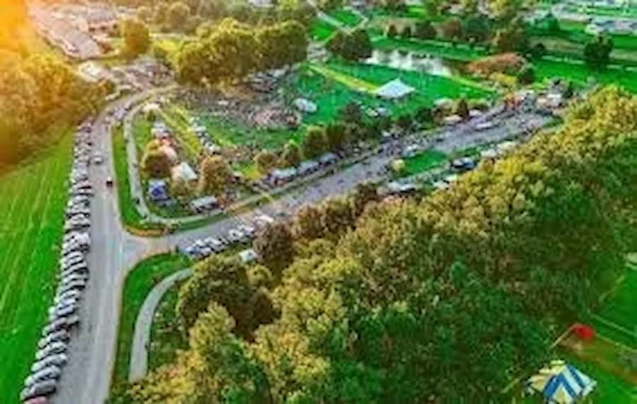 Aerial view of a park, parking lot, and surrounding greenery in a community setting.