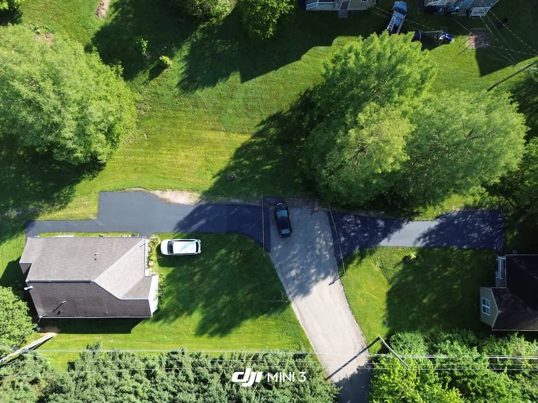 Residential driveway sealcoating project in Athens OH showing freshly sealed asphalt from above.