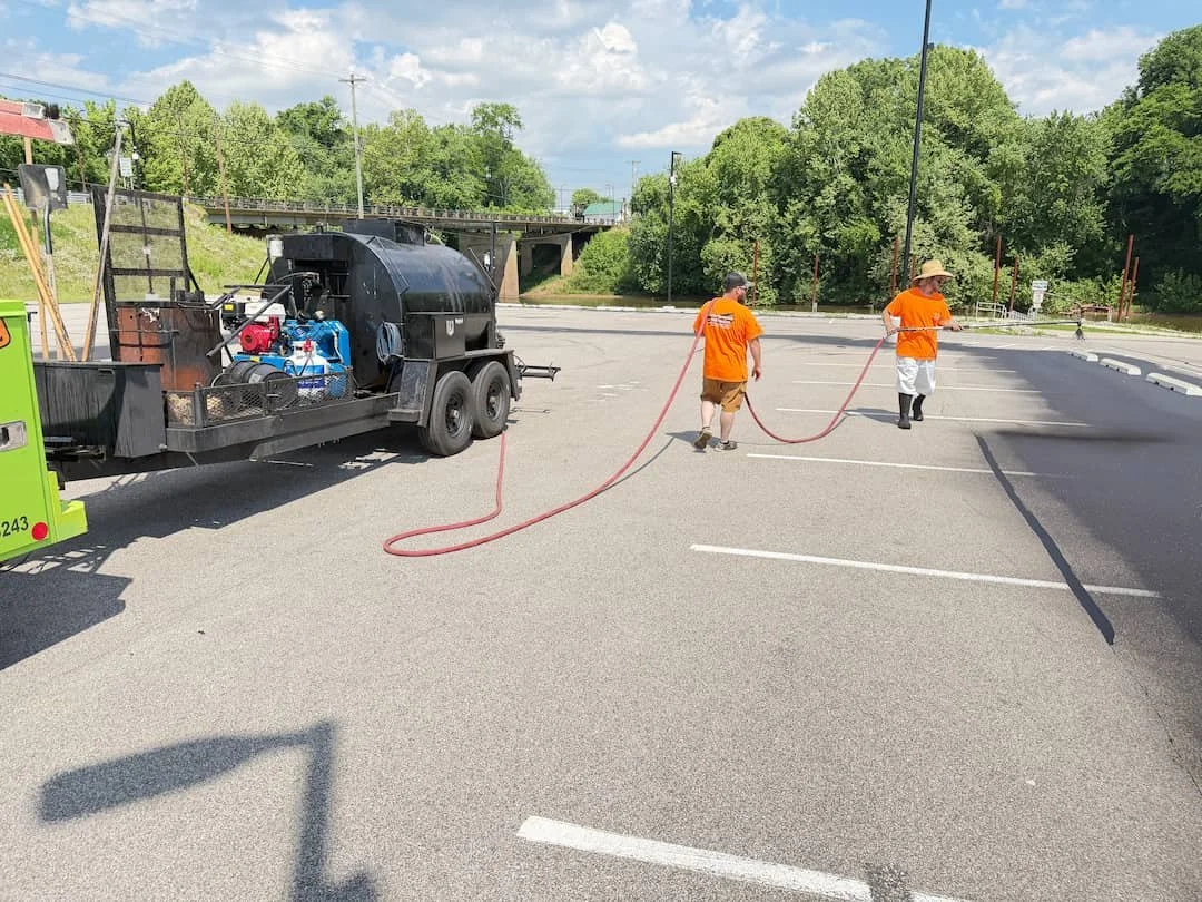 Parking lot sealcoating project in Ravenswood WV with fresh black asphalt and commercial-grade sealer application.