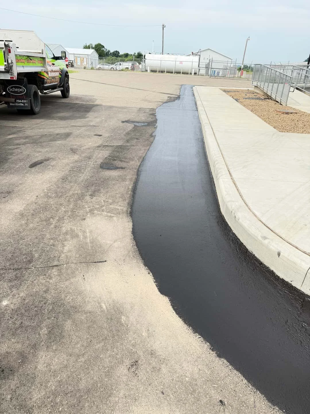 Parking lot sealcoating edge work at Gallia-Meigs Regional Airport in Gallipolis OH with hand-cutting around curbs and concrete.