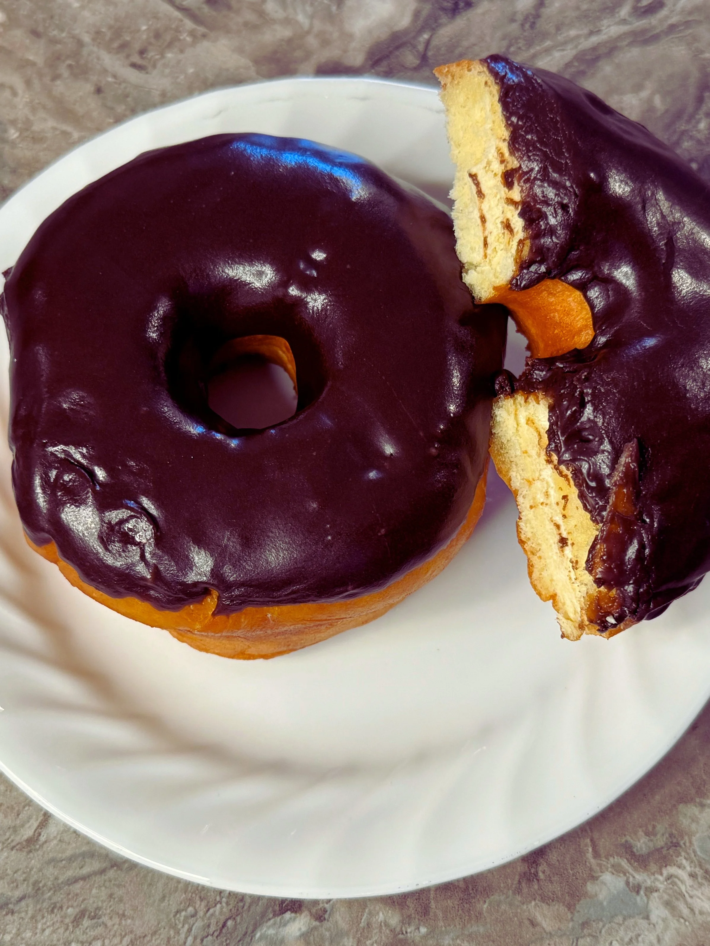 Two chocolate-glazed donuts with a yellow base on a white background.