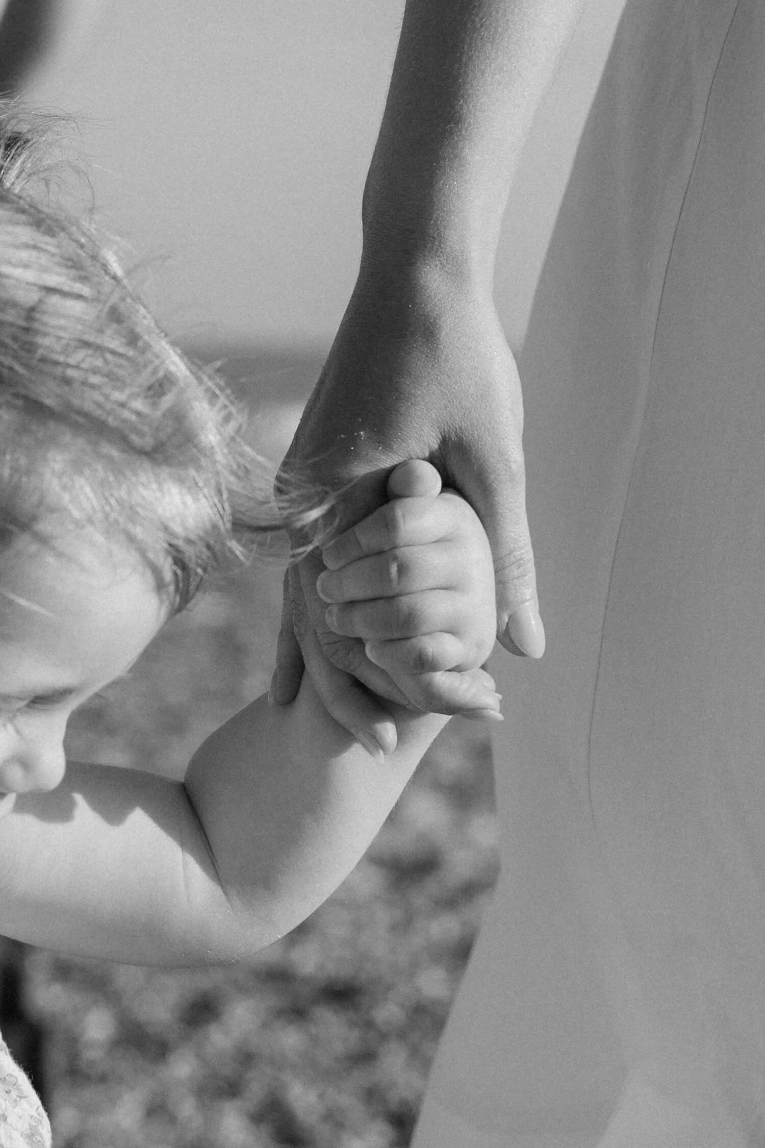 A young child holding hands with an adult, with their faces partially visible in a black and white photo.