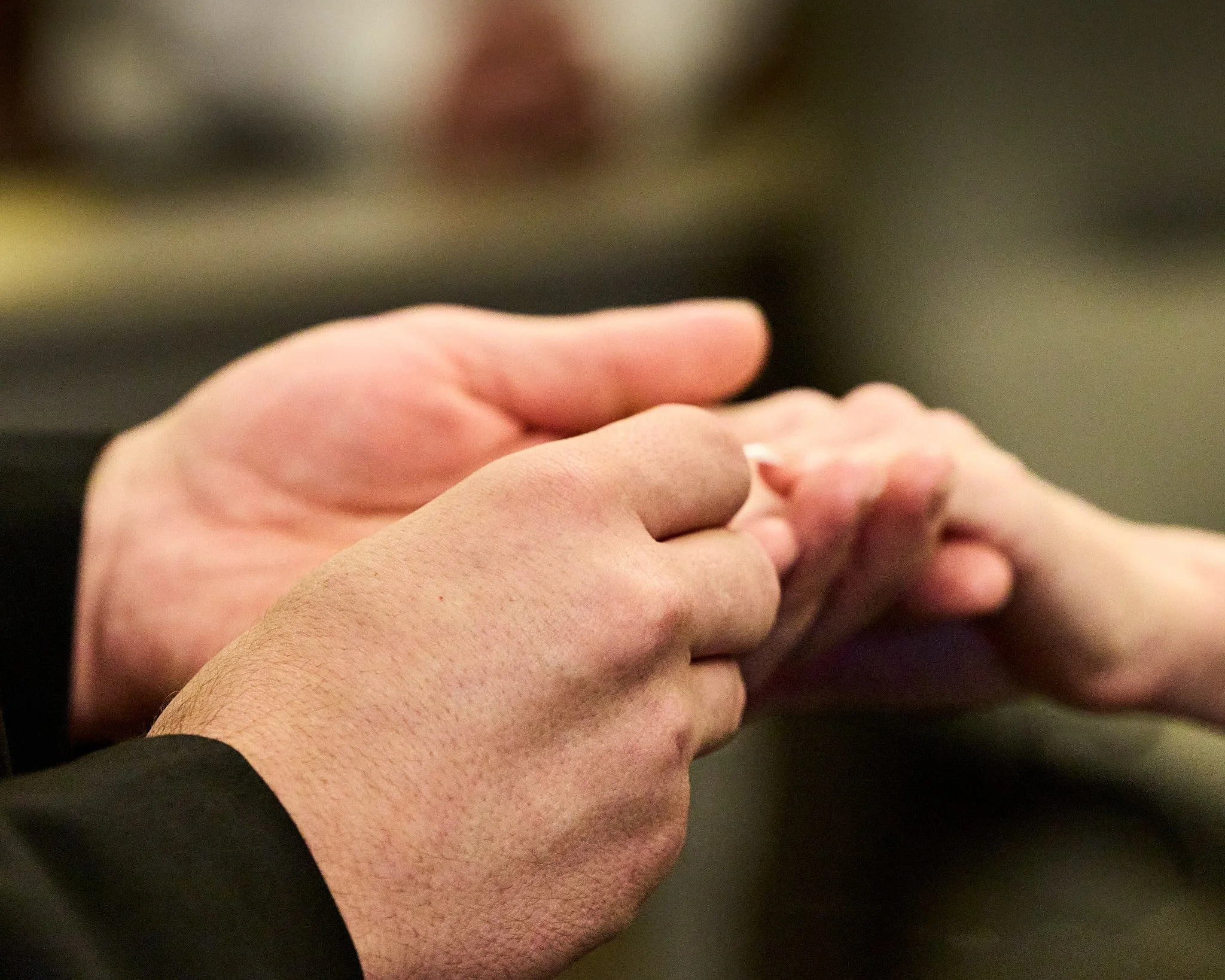 Close-up of hands with one hand gripping the other, against a blurred background.