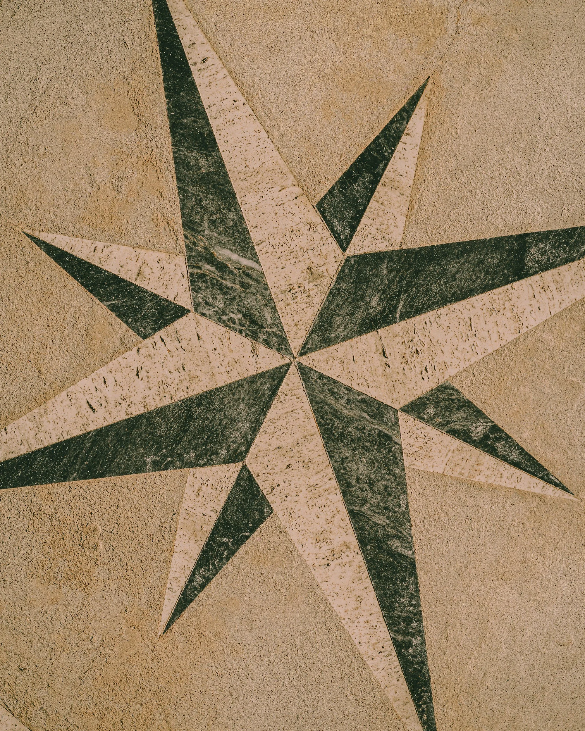 Stylized star mosaic pattern on a beige textured wall.