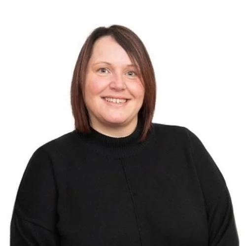 A woman with shoulder-length brown hair wearing a black sweater, smiling against a white background.