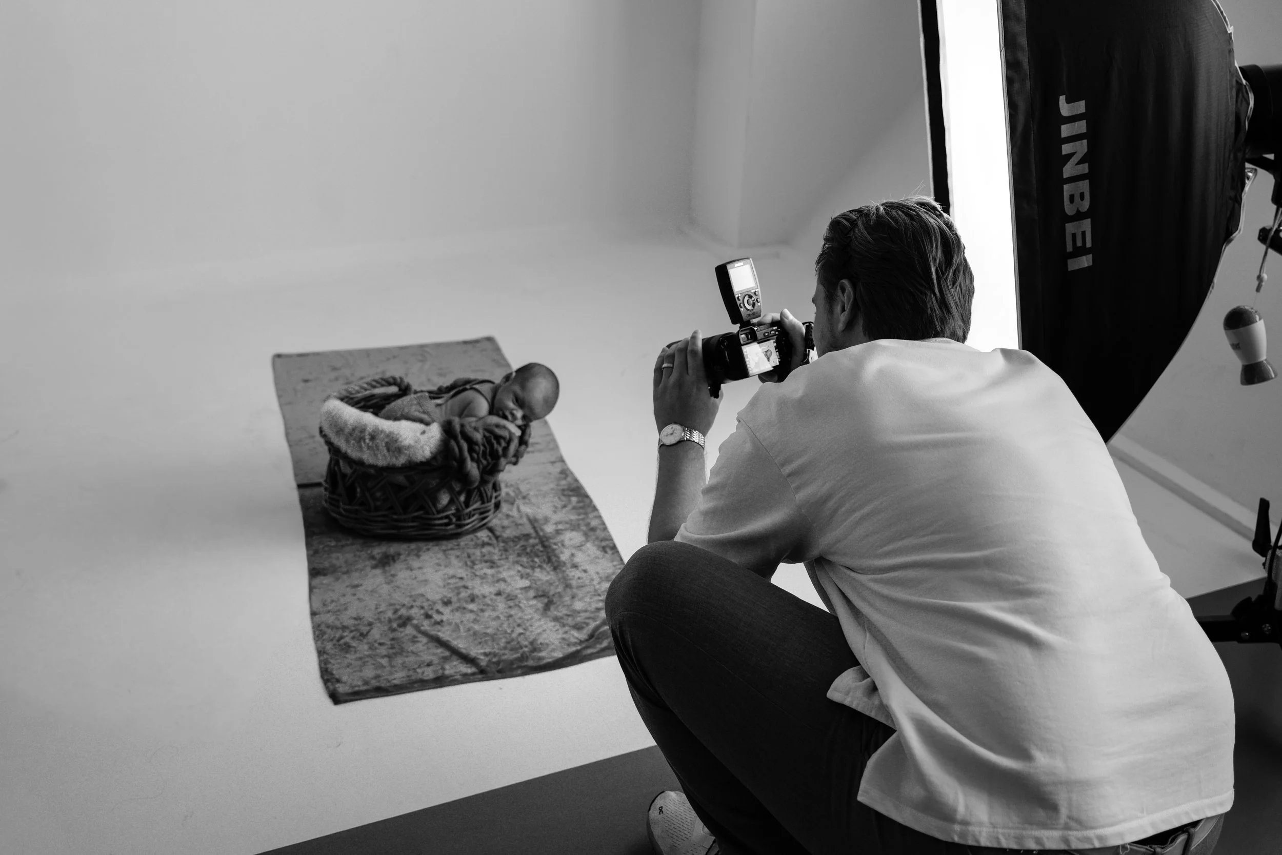 Fotograf, Robert Kaysser, macht ein Fotoshooting eines neugeborenen Babys, das in einem Korb liegt, im Studio in Schwenningen, schwarz-weiß-Aufnahme.