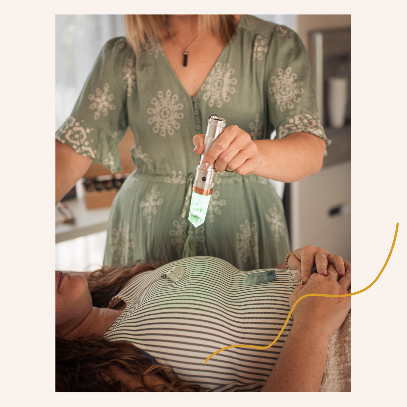 A woman lying on a bed with her hands folded on her chest, receiving a crystal healing session with Jackie holding a lighted crystal wand above her body.