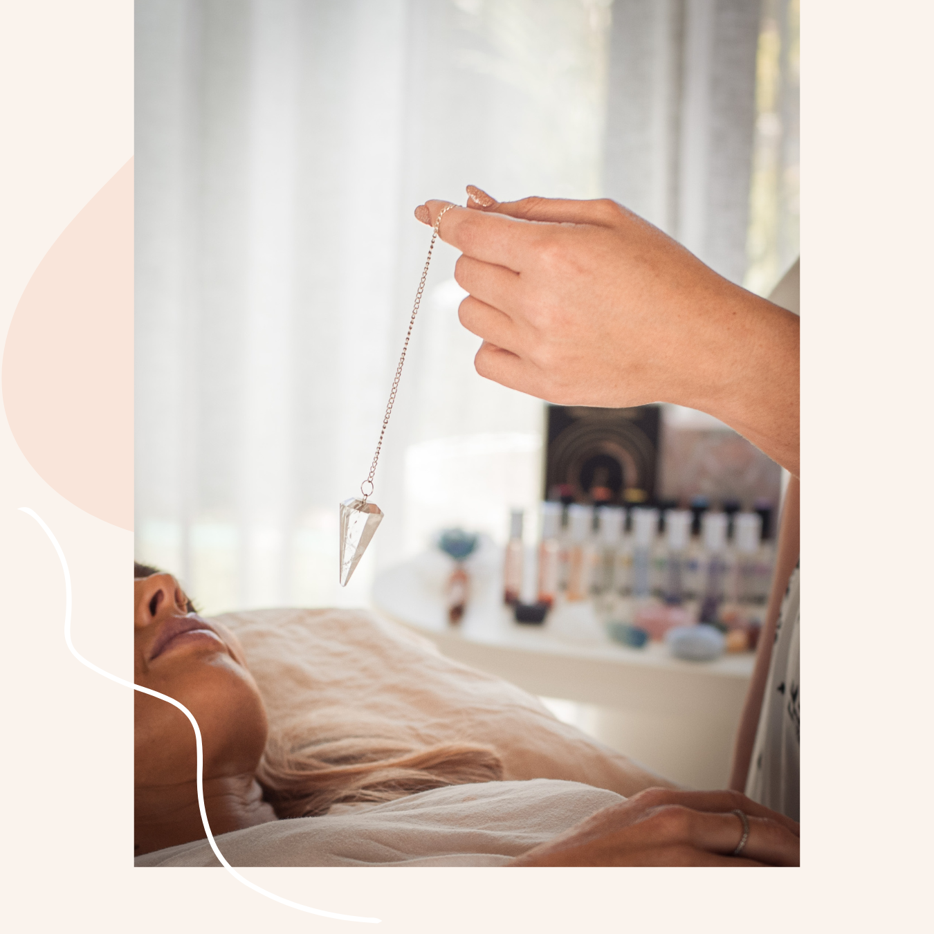 A woman lying on a massage table with a crystal pendulum held above her face by Jackie to balance a chakra.