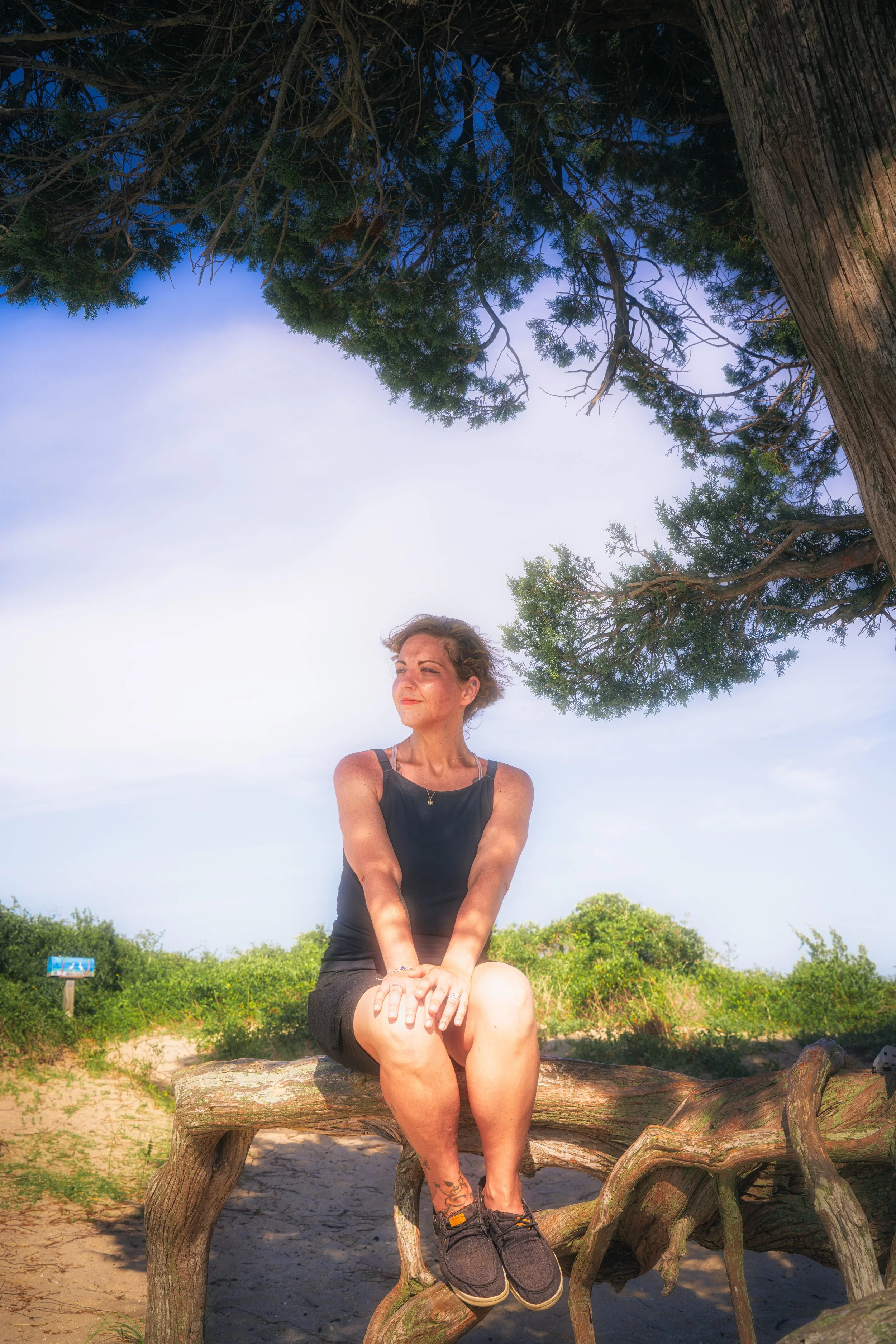 Soft natural light falls through tree cover as the subject sits quietly within a shaded outdoor setting.