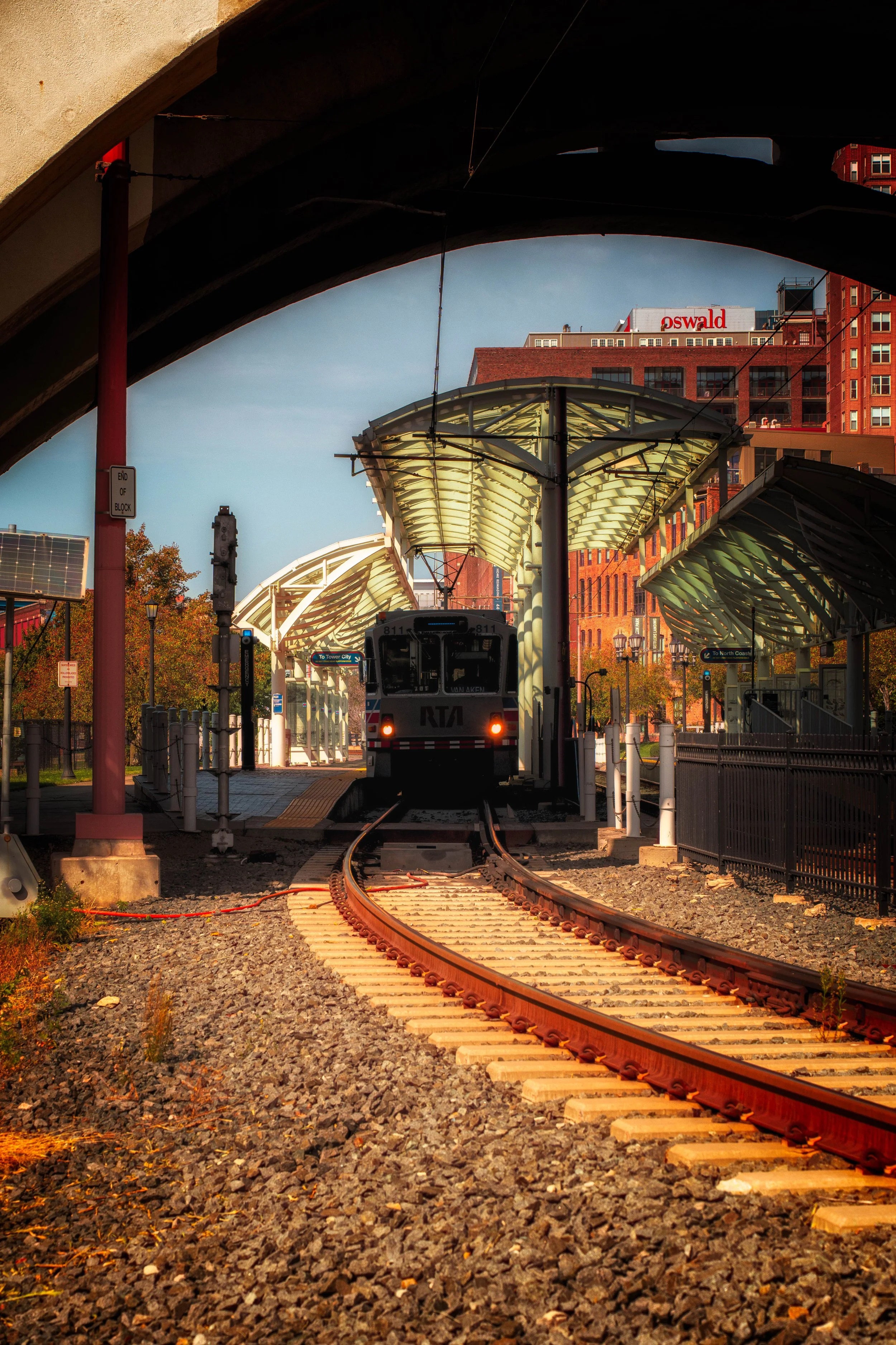 Rail lines curve through an urban corridor, guiding the eye through layers of architecture and movement.
