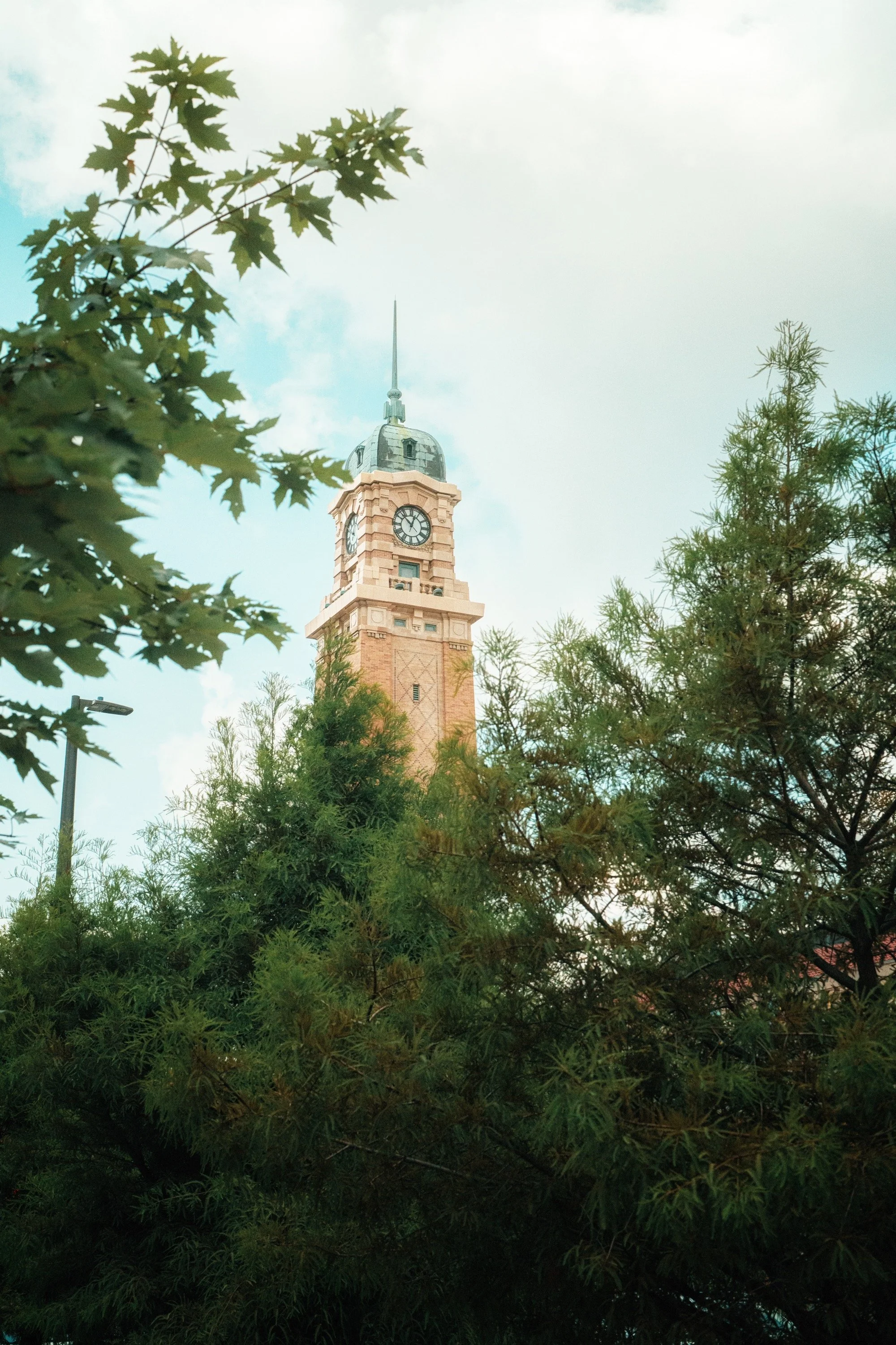 Historic Cleveland clock tower framed by green trees beneath a bright sky.