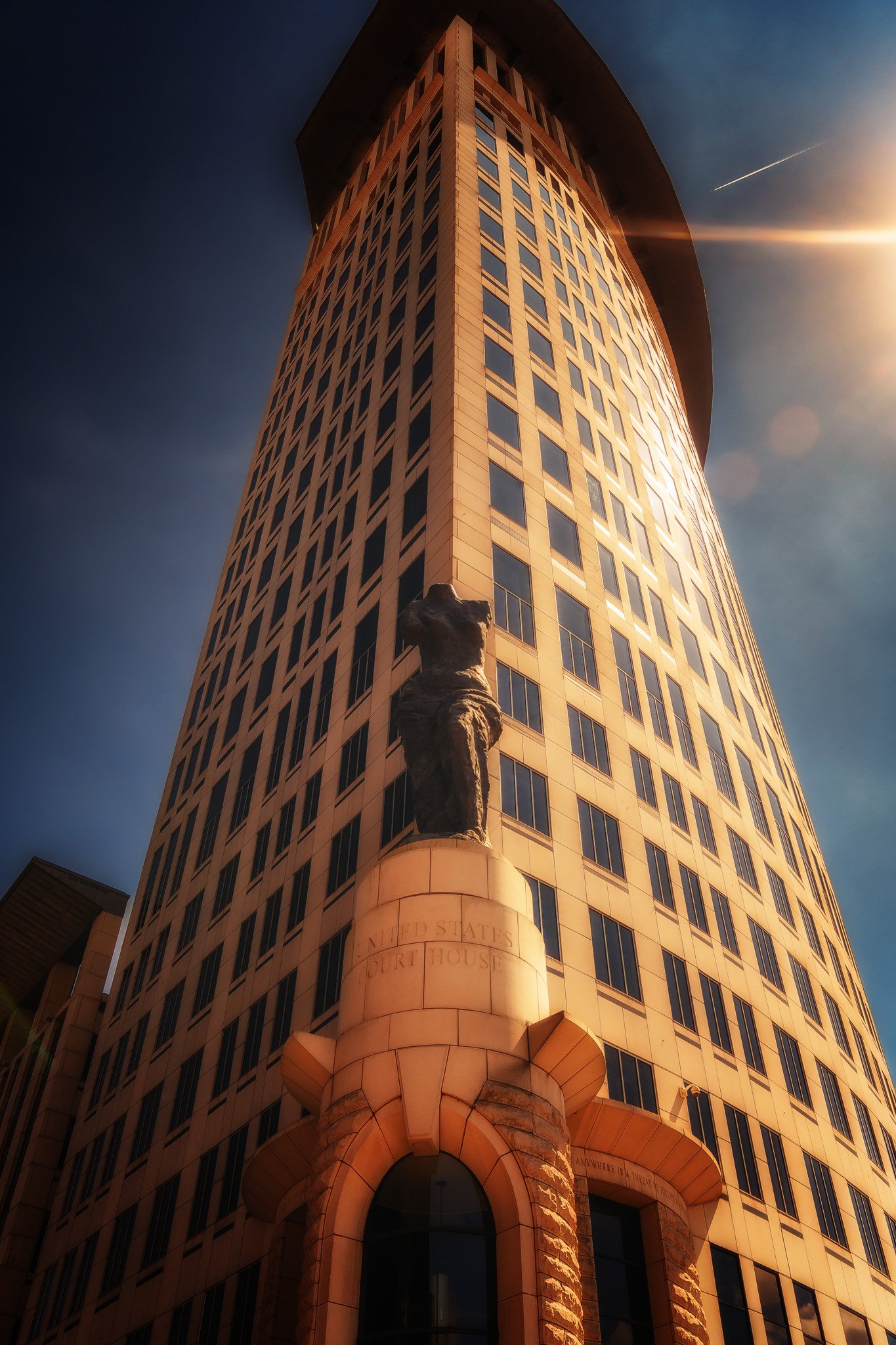 A towering building stretches upward between surrounding structures, emphasizing scale and vertical design in the city skyline.