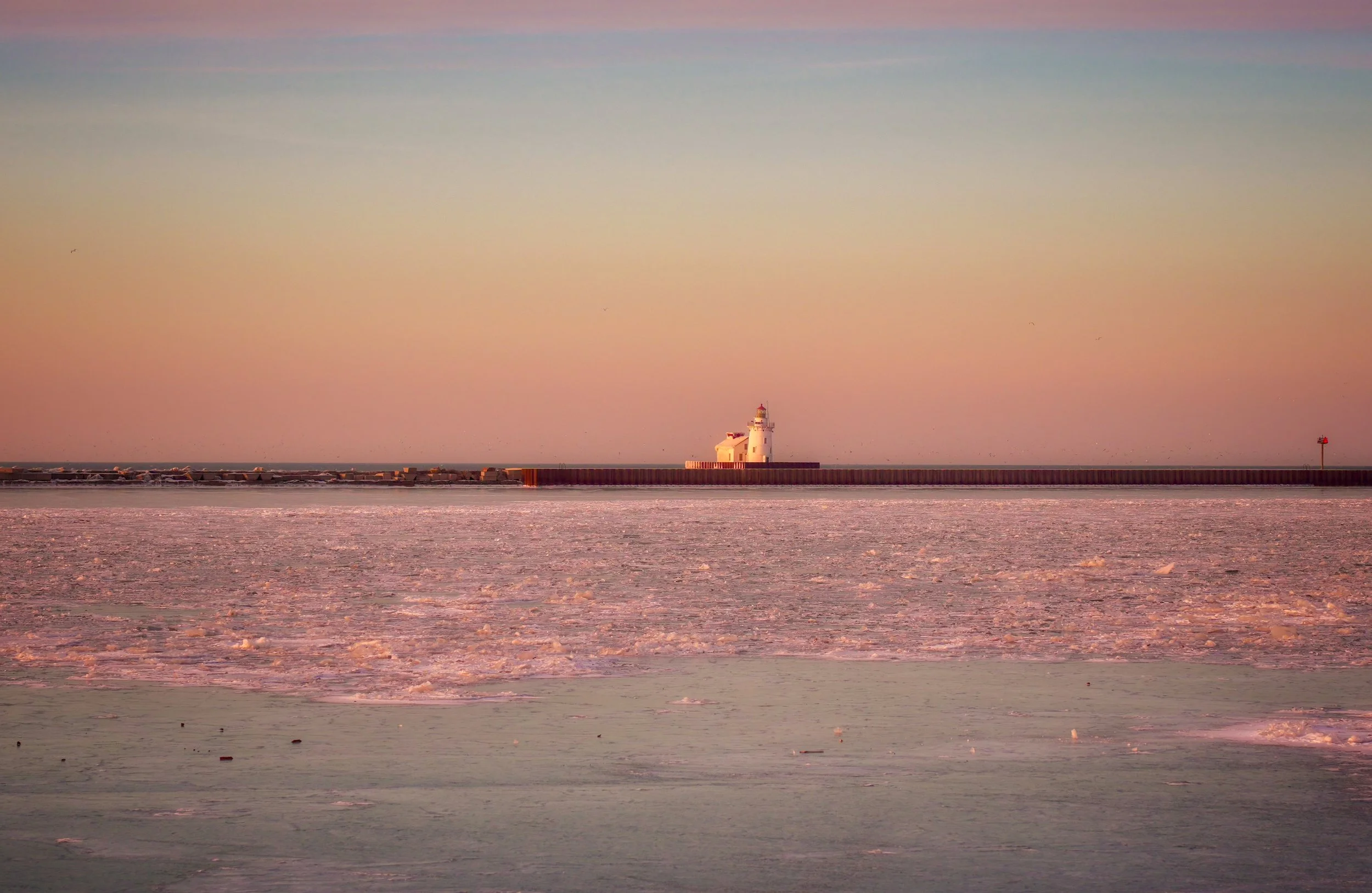 A lighthouse stands against the fading sunset along the Lake Erie shoreline near Cleveland, Ohio, as evening light disappears over the water.