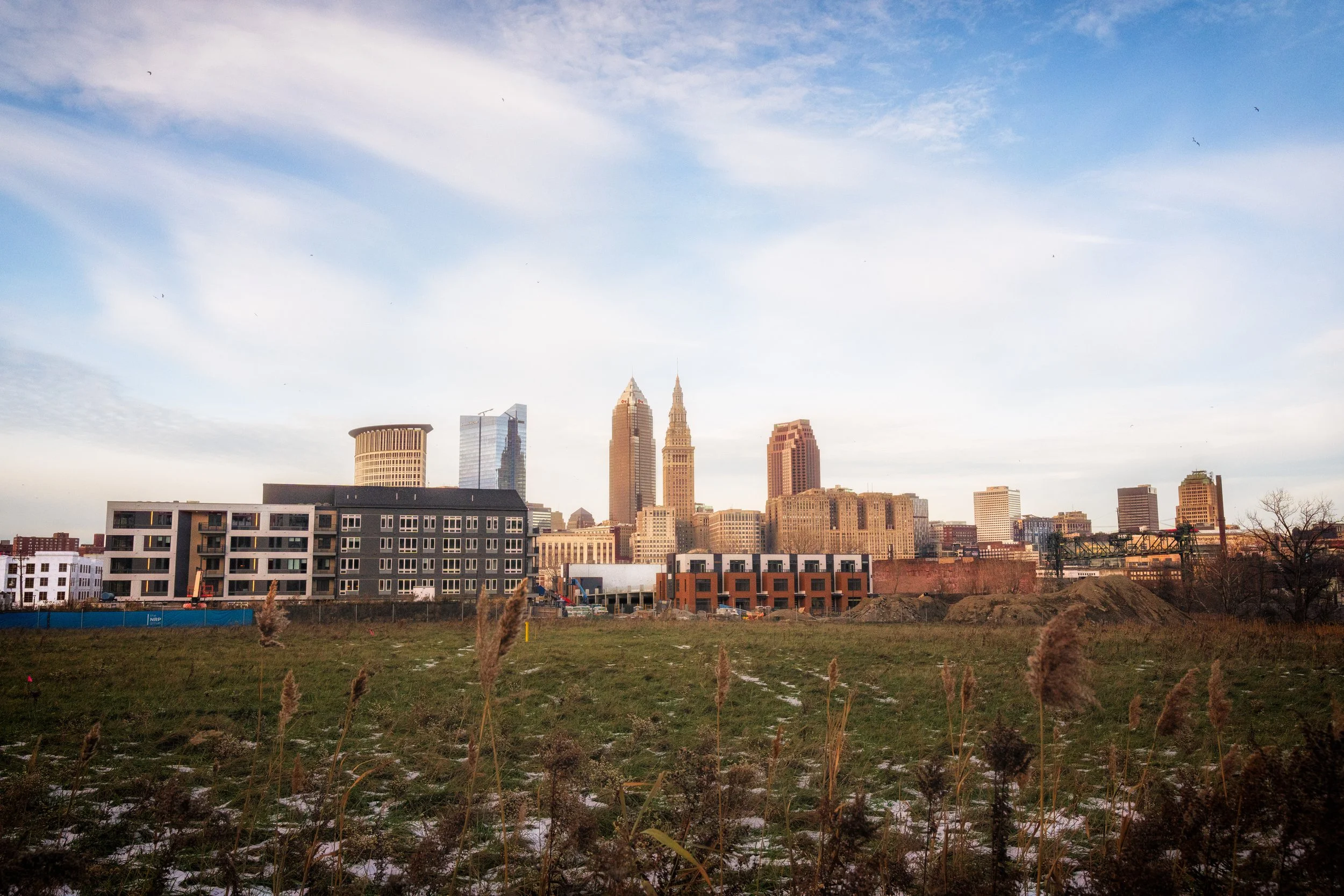 The Cleveland skyline rises beyond open ground, highlighting the meeting point between urban space and the surrounding landscape.