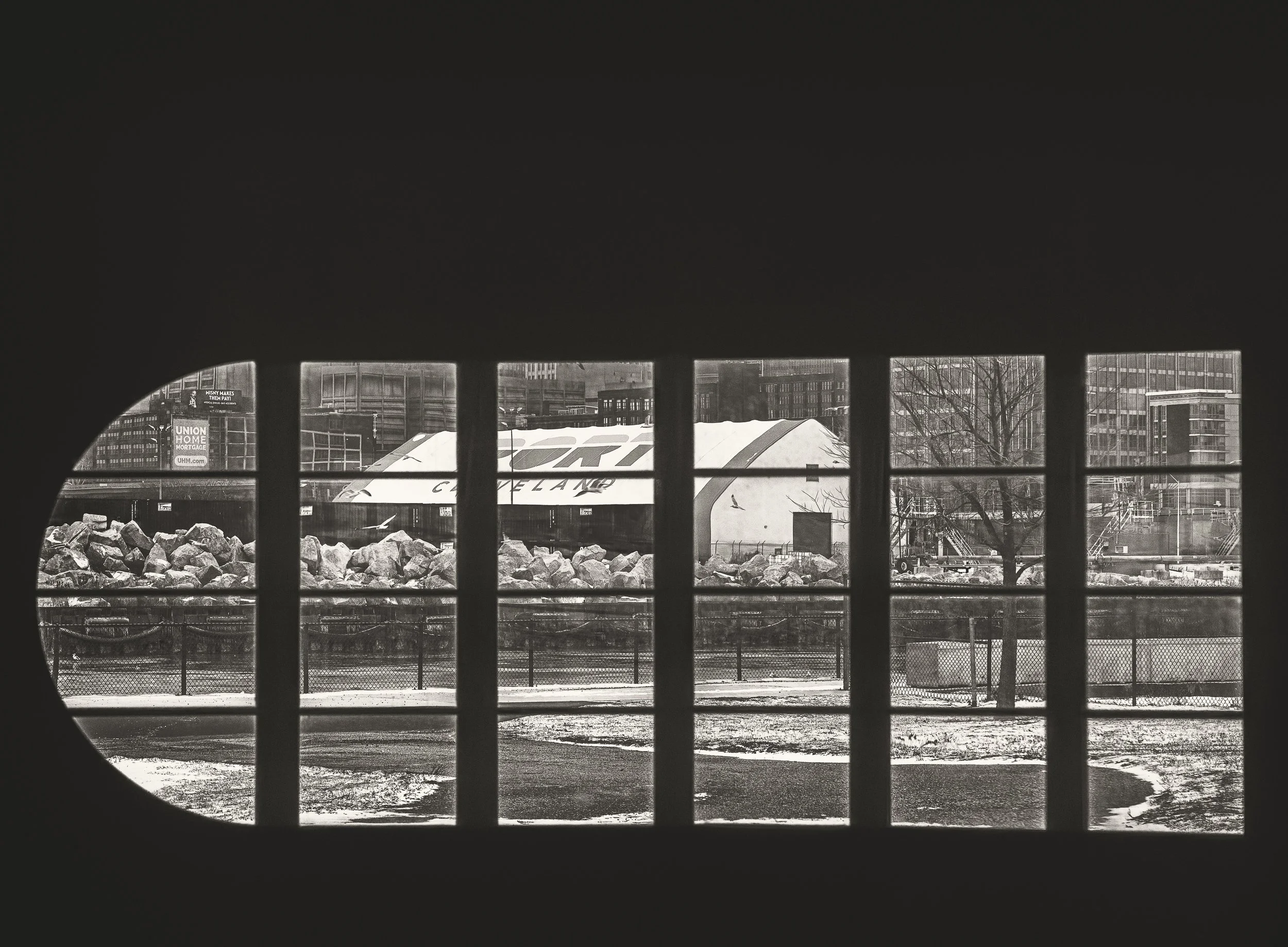 An exterior scene appears through industrial windows, blending interior shadow with the city beyond.