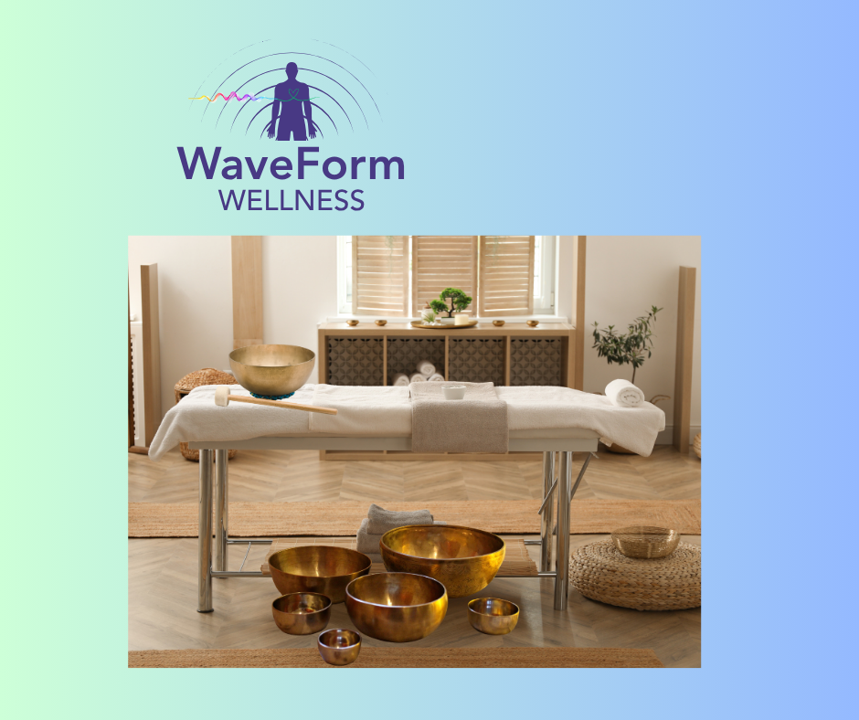 A wellness massage room with a massage table, bowls for sound therapy, and natural decor including plants and window blinds.