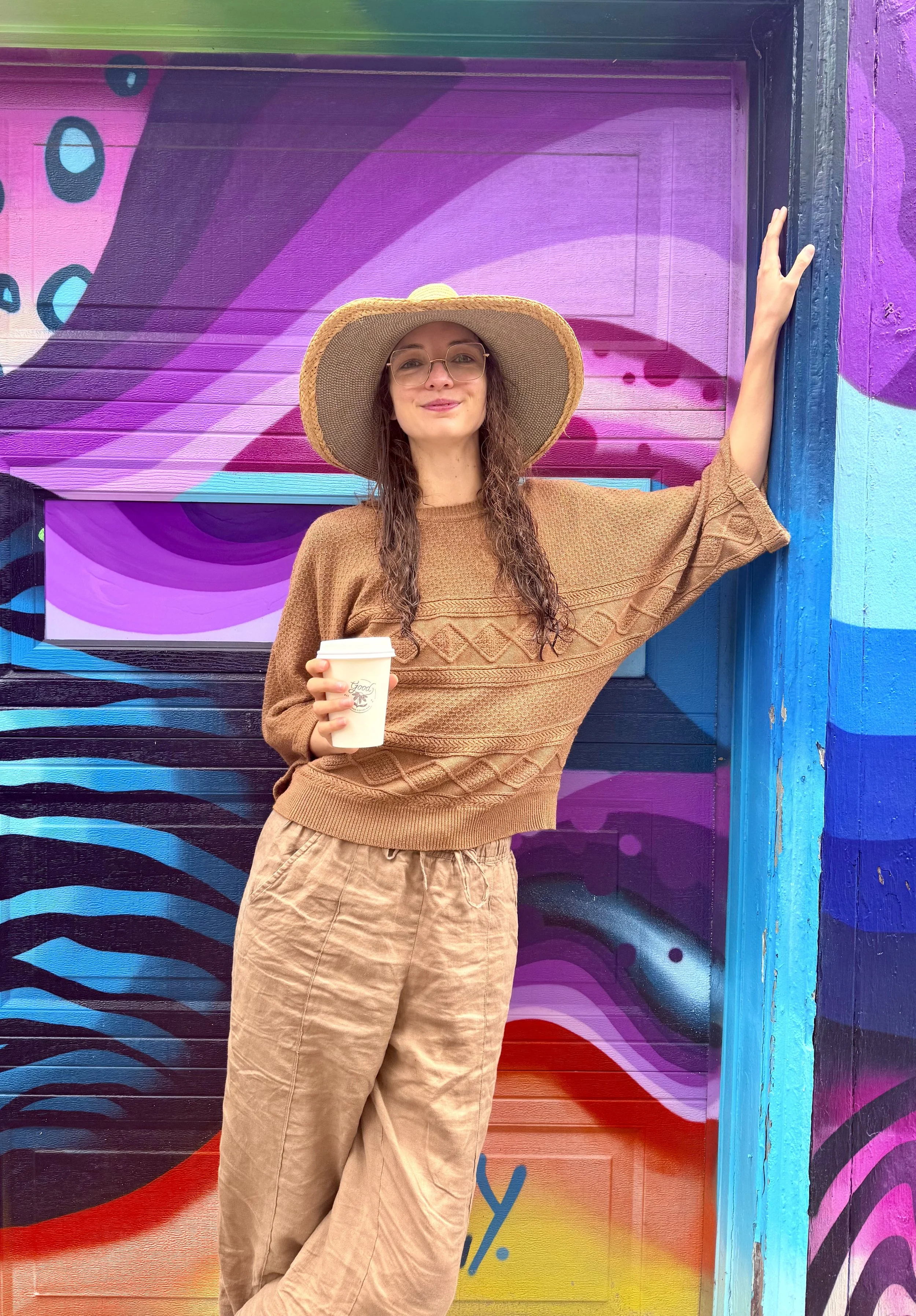 Abi the owner of SomaPsyche by colorful wall
