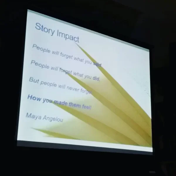 Projection screen displaying a presentation slide titled 'Story Impact' with bullet points about memory and feelings, and a quote by Maya Angelou.