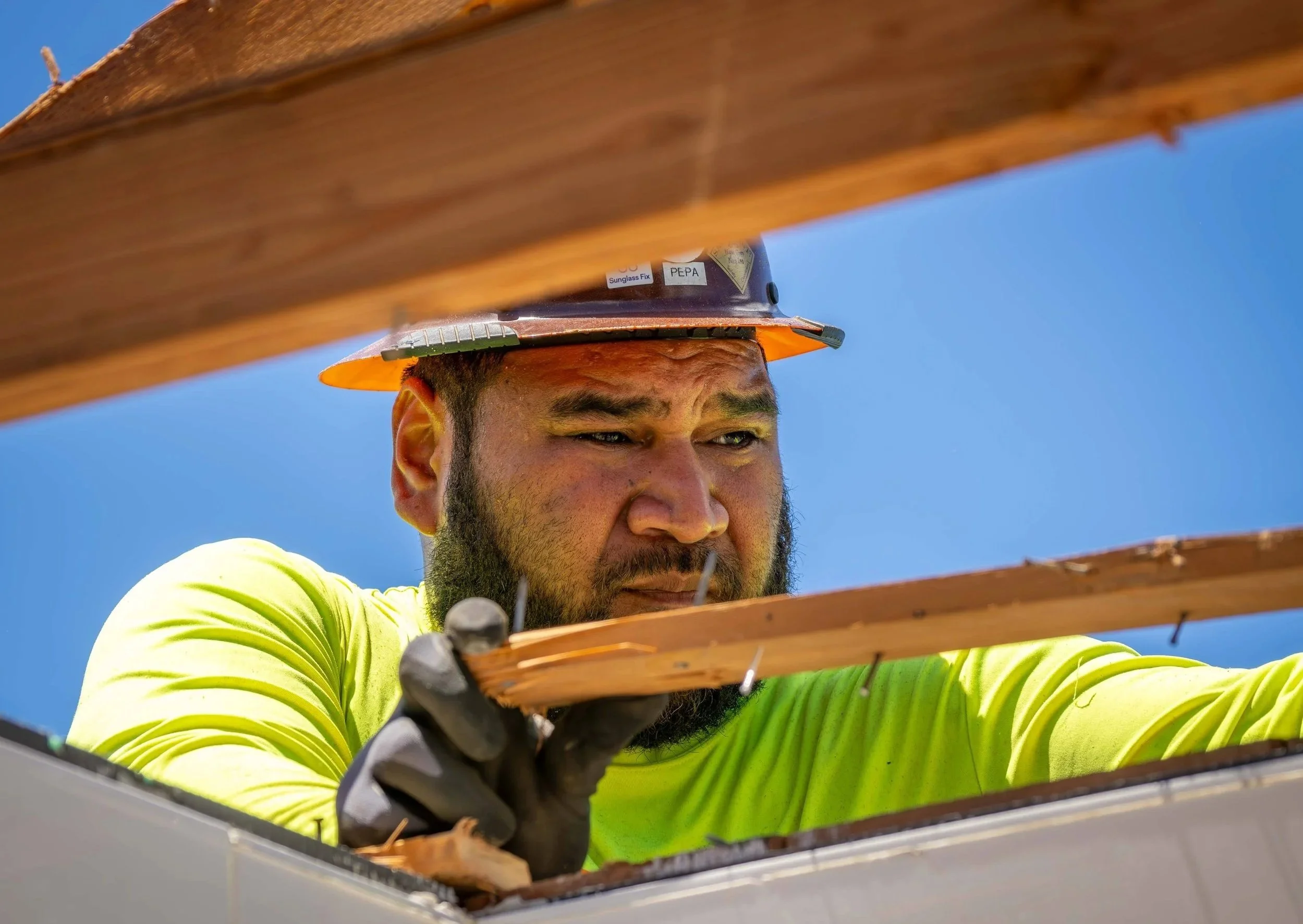 A close-up image of a man removing wood with nails on a deconstruction project site.