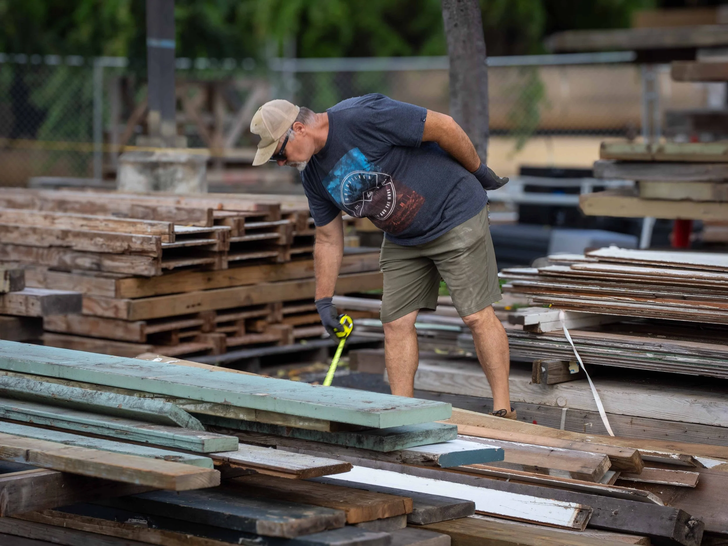 A man shopping for lumber in the LumberYard at Re-use Hawai‘i using a measuring tape.