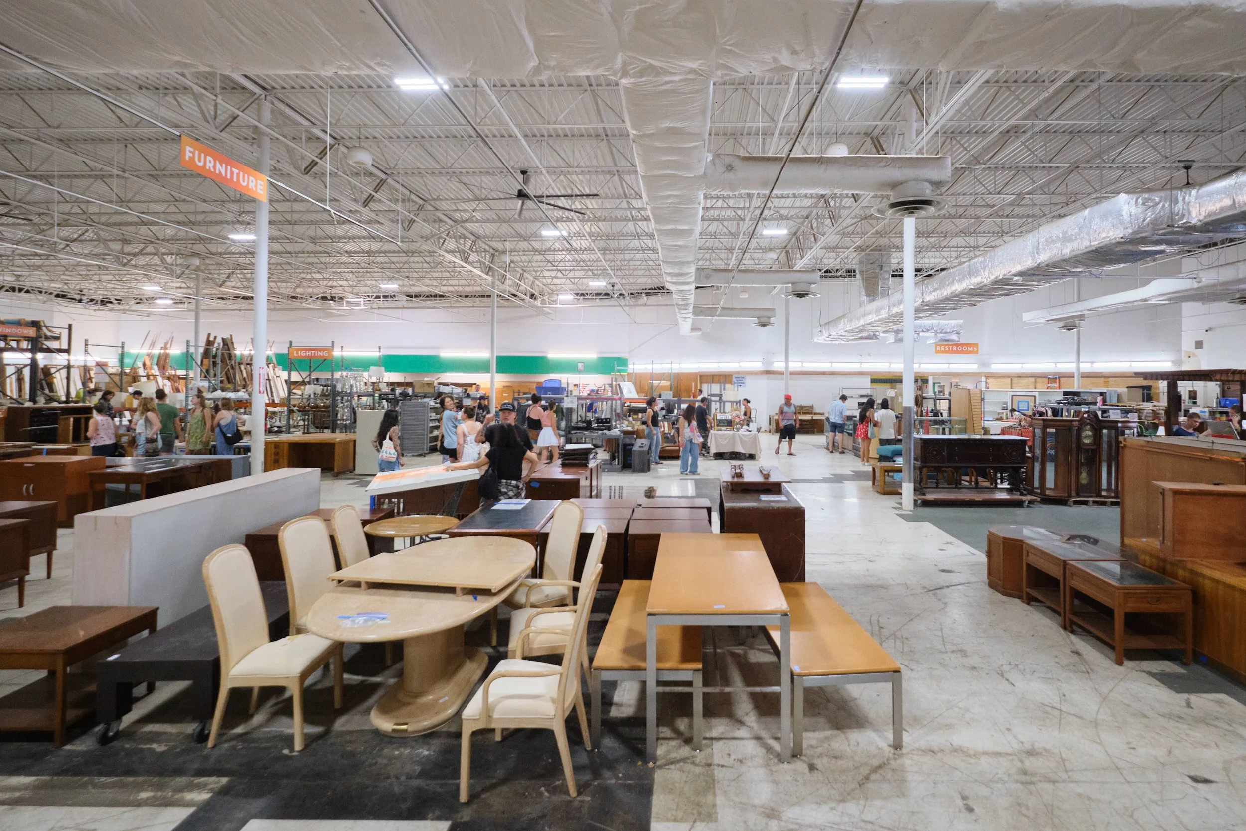 Wide angle shot of inside the Re-use Hawai‘I warehouse showcasing large amounts of  furniture available.