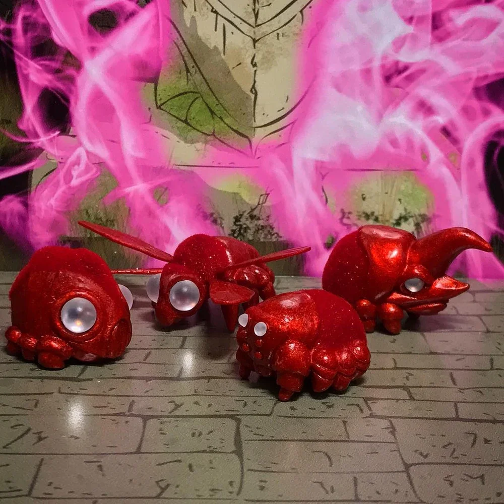 Four small toy creatures painted red, resembling animals with eyes made of white beads, placed on a surface with a brick pattern. Behind them, there is a background with pink, purple, and green swirling smoke or mist and a sketch of a face or mask.