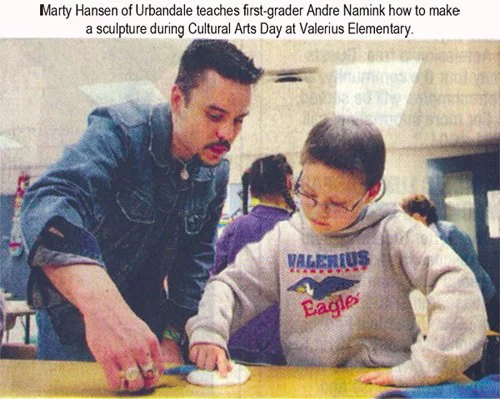 Man instructing a young boy on how to make a sculpture during Cultural Arts Day at Valerius Elementary.