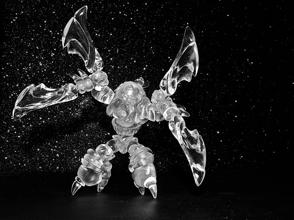 Clear glass sculpture of a dragonfly with detailed wings set against a starry black background.