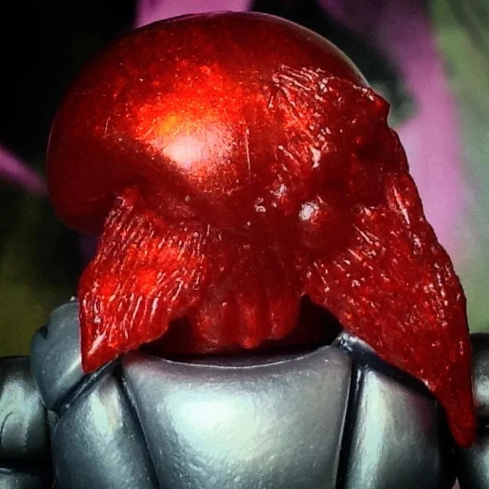 A close-up of a ripe red cherry tomato with a green leafy background.