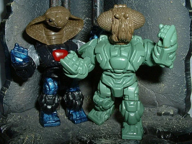 Two toy action figures with animal heads and armored bodies standing on a rocky surface.