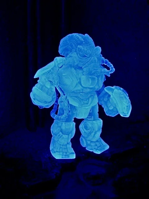 Glowing blue sculpture of a humanoid robot with helmet, armor, and large fists, illuminated in dark setting.