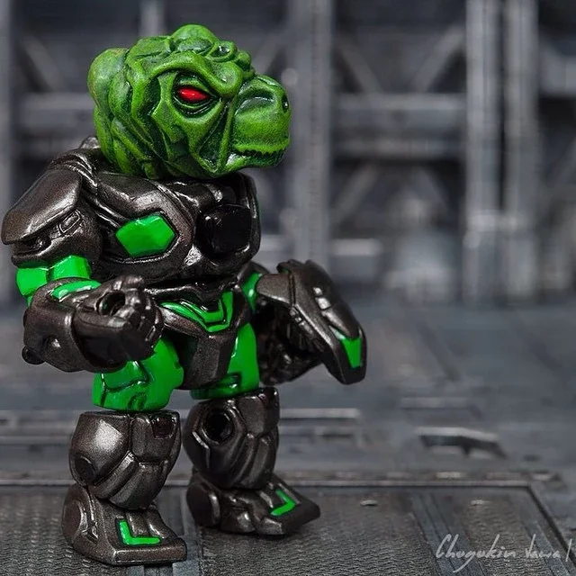 A toy figure of a green, robotic dinosaur with red eyes, dressed in a black and green armor suit, standing on a gray industrial background.
