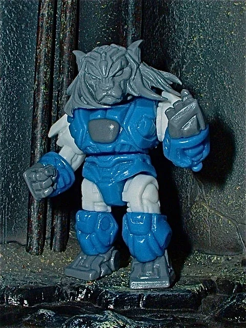 A detailed action figure of a beast-like creature with a lion's face, gray fur, and muscular gray and blue armor, posed in front of a textured background.