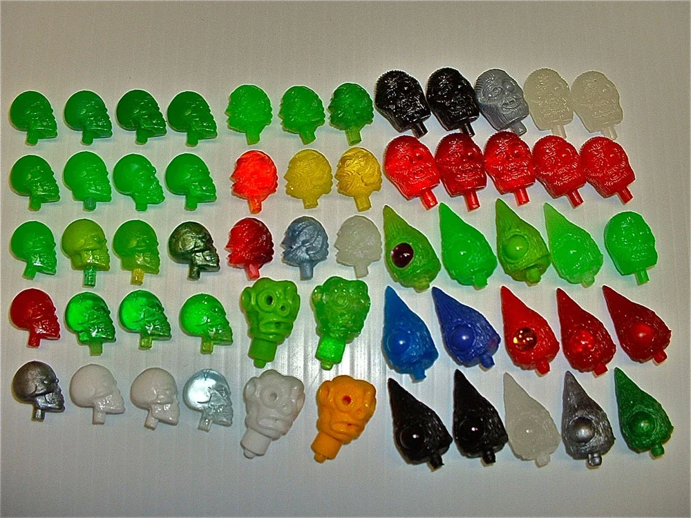 Colorful skull-shaped gummy candies arranged in rows by color on a white surface.