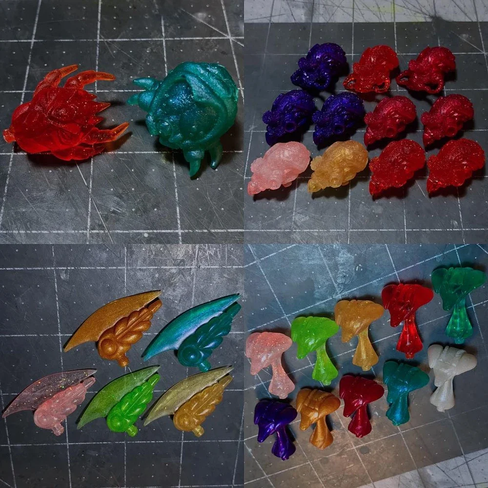 Colorful miniature game pieces of creatures and items arranged on a grid cutting mat.