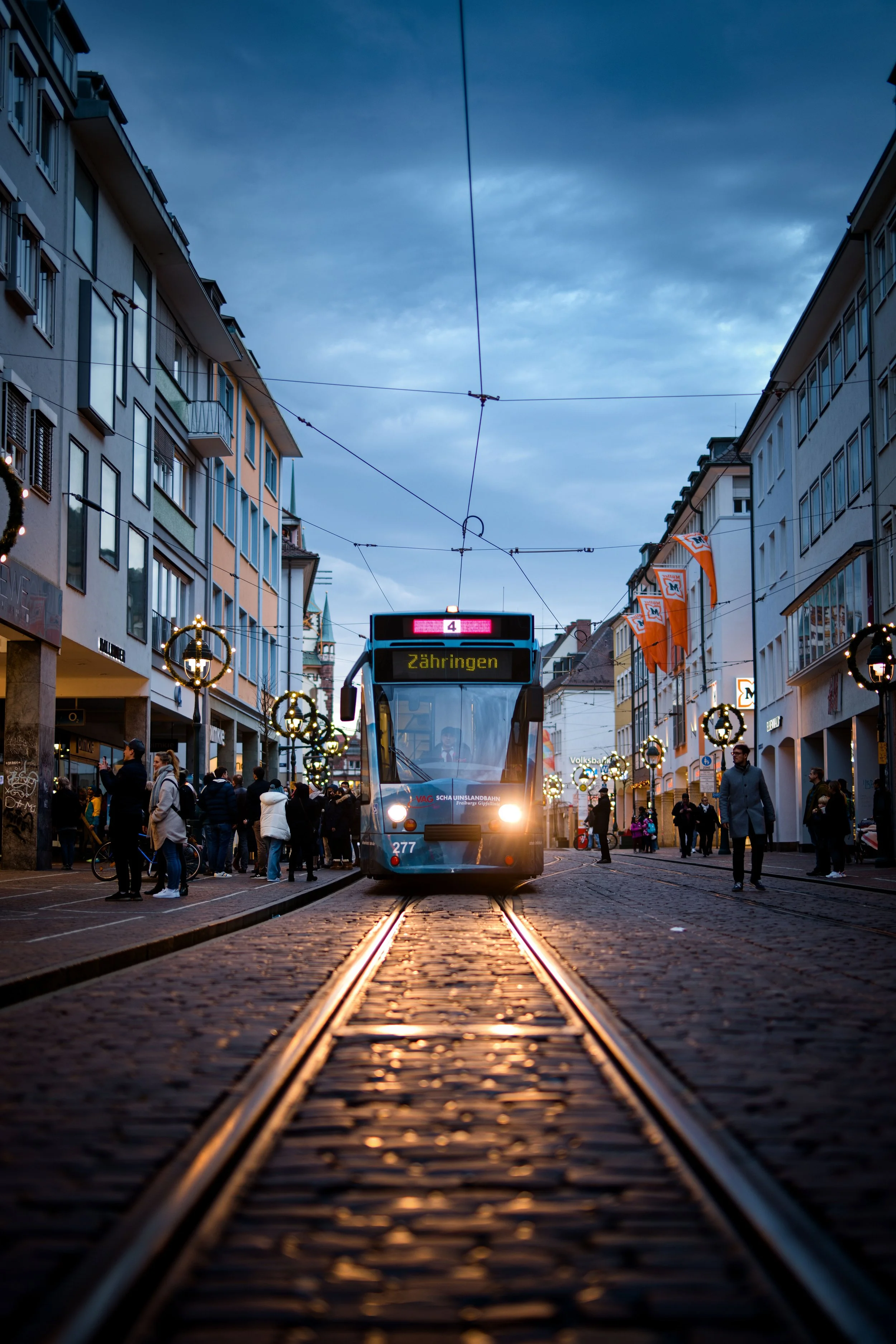 Straßenbahn in einer belebten Innenstadtstraße bei Dämmerung