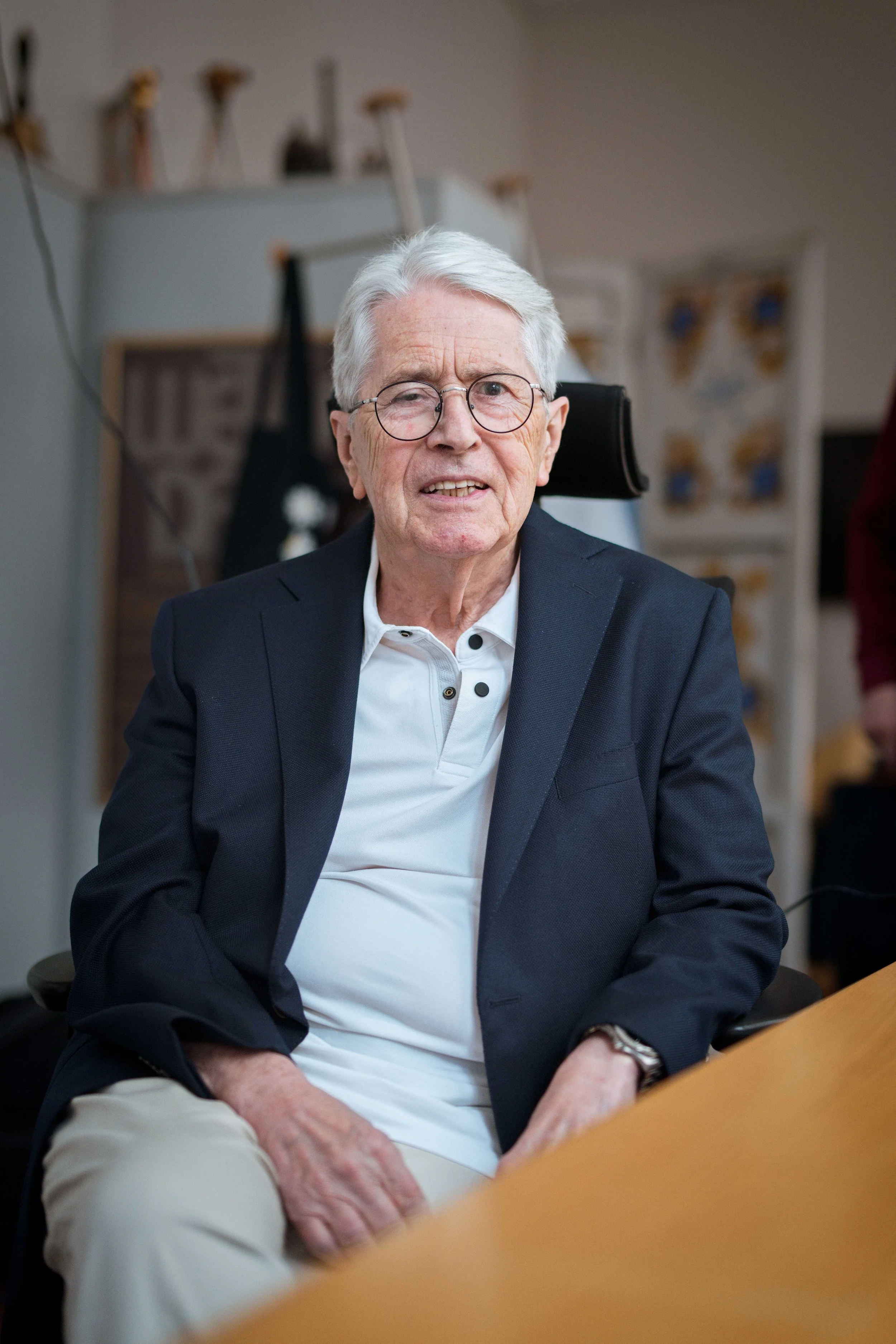 Frank Elstner mit Brille und Anzug sitzt an einem Tisch. Fotograf Julien Ruf aus Villingen. Portrait von Frank Elstner bei einer professionellen Fotosession