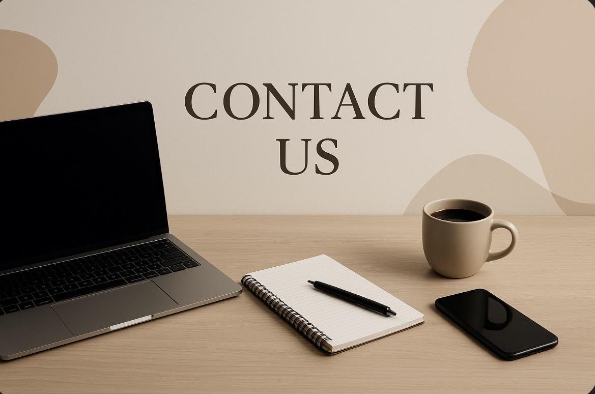 A workspace with a laptop, a notepad with a pen, a coffee mug, and a smartphone on a wooden desk with a "Contact Us" sign on the wall behind.