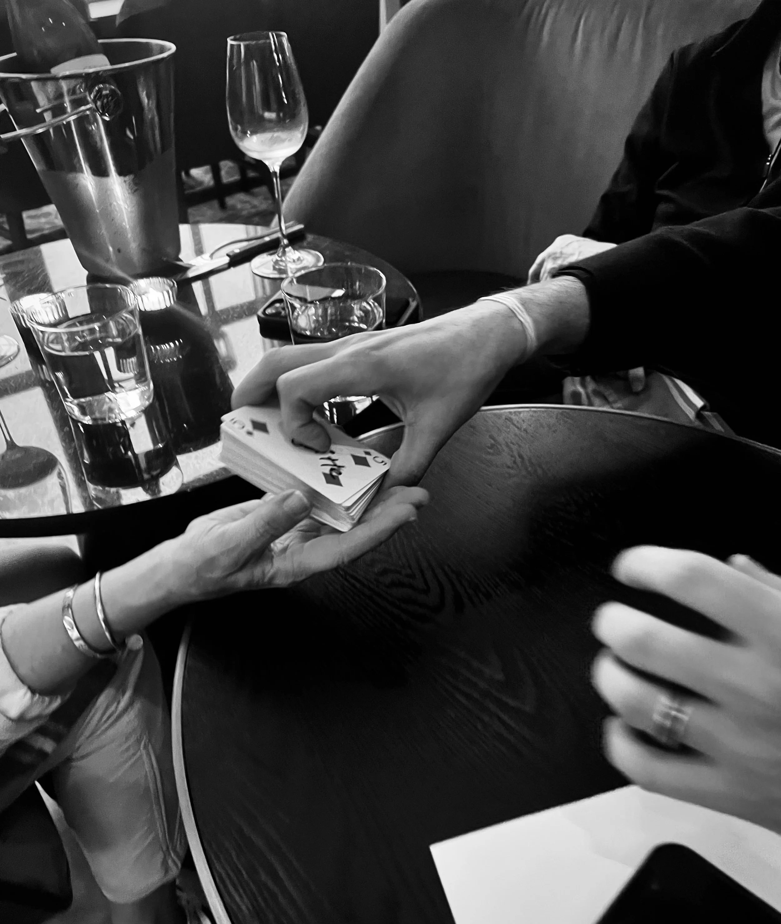 People playing cards at a table with glasses of water and wine