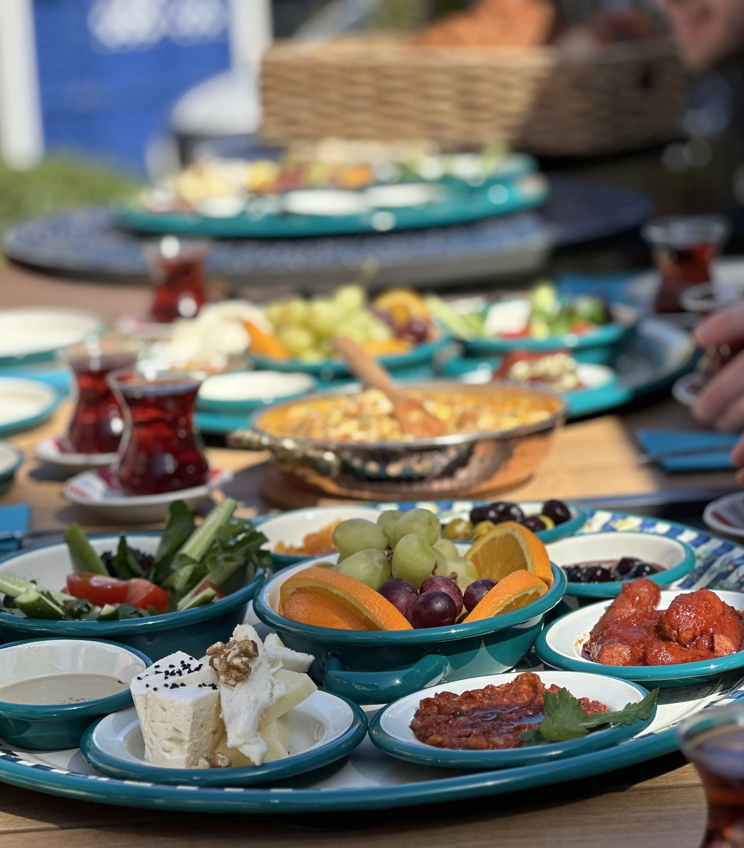 Traditional Turkish breakfast at Berna’s Bakery in Issaquah, featuring cheeses, olives, fresh fruit, salads, and Turkish tea served on turquoise plates.
