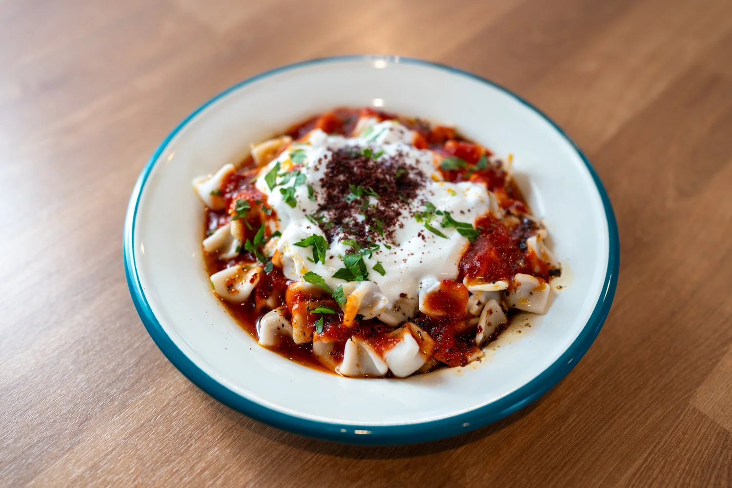 Manti Plate at Berna's Bakery & Cafe in Issaquah, beef dumplings topped with garlic yogurt and tomato sauce