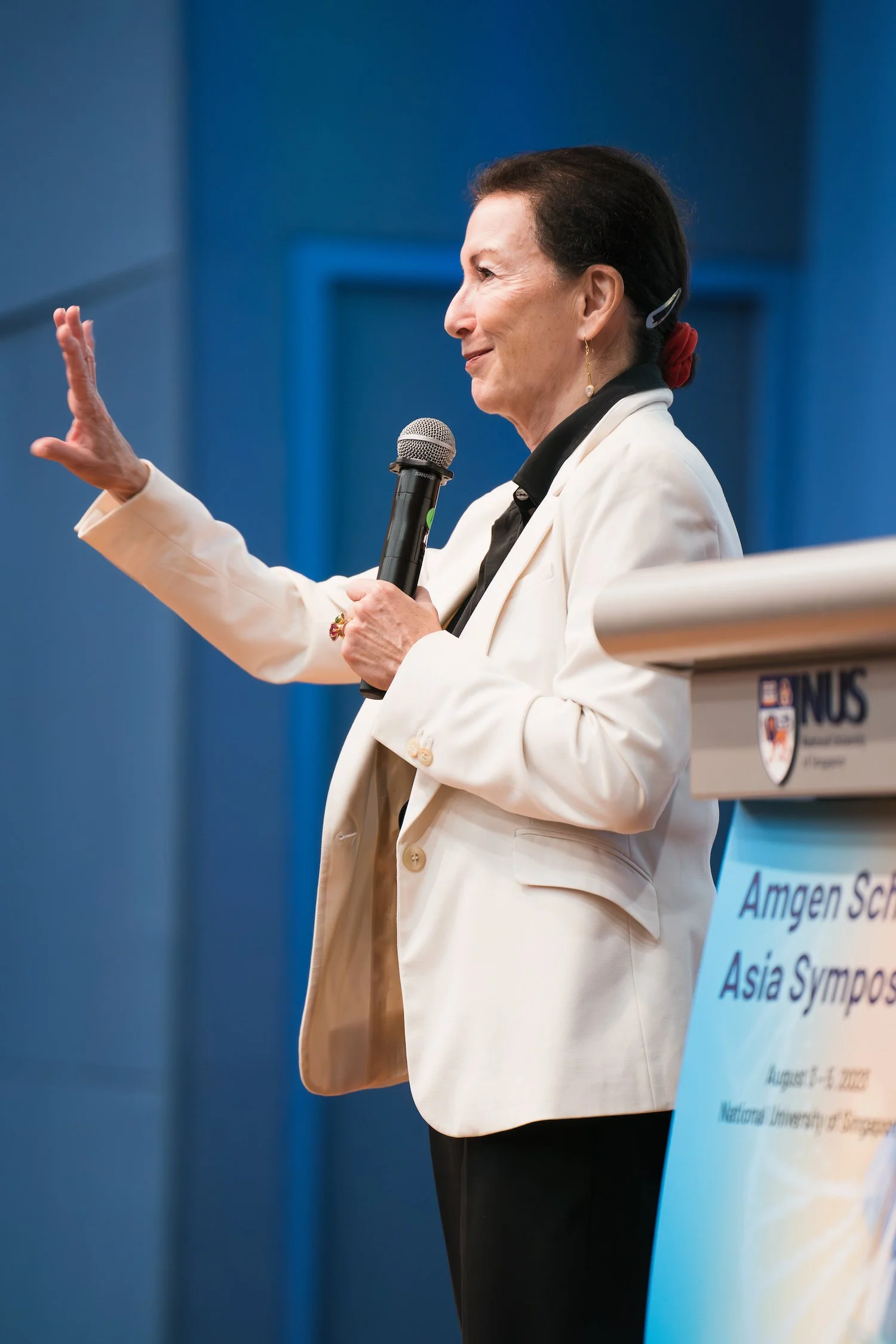 Woman speaking into a microphone at a scholars symposium, conference photography by David Pierre Studio