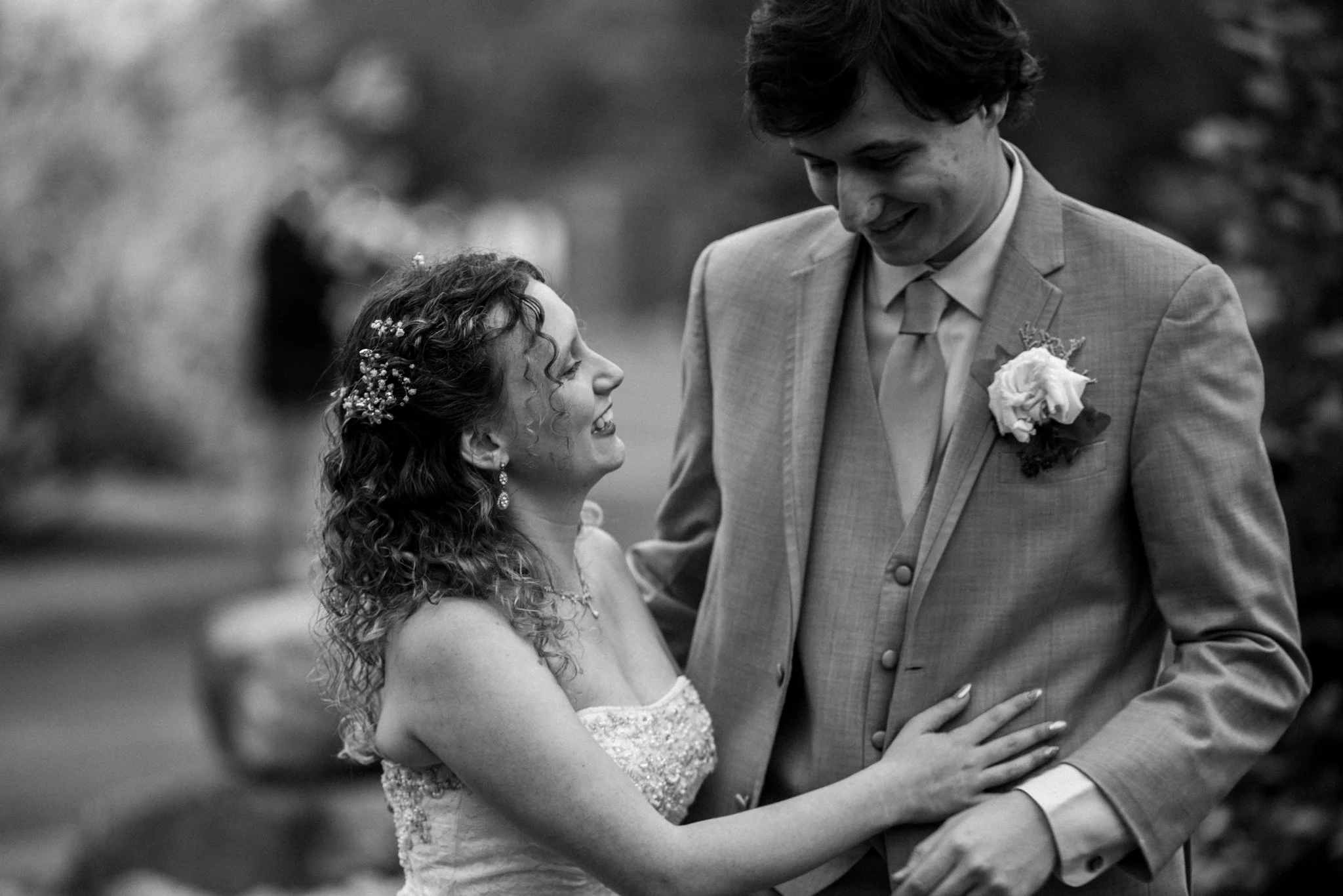 Black and white photo of a bride laughing as she looks up at her groom on their wedding day, captured by David Pierre Studio