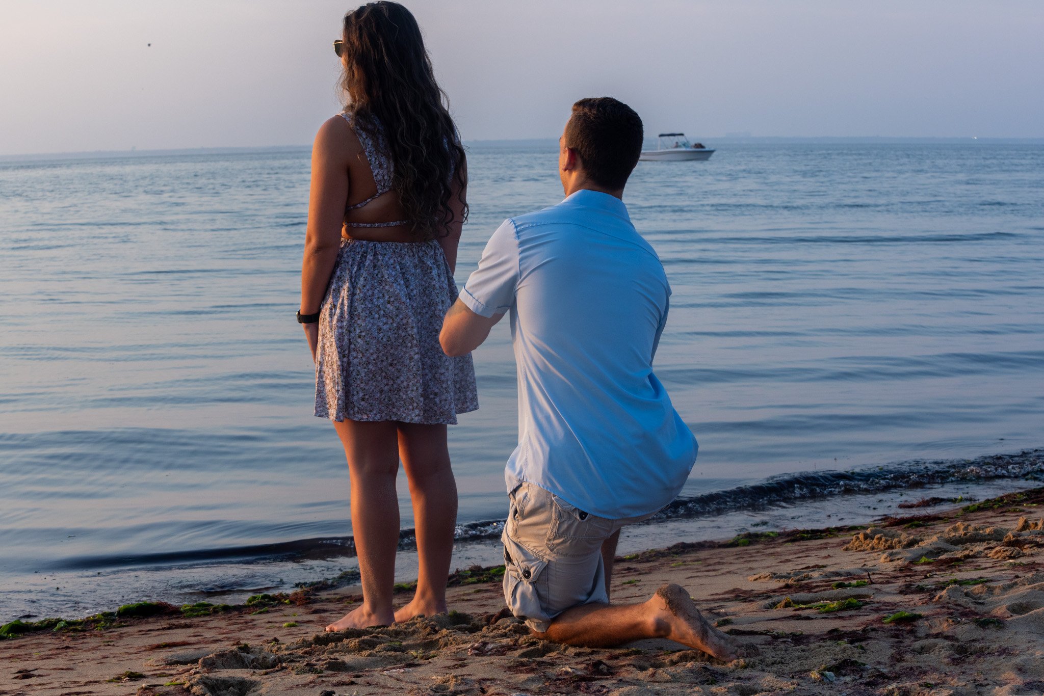 Man kneeling to propose to his girlfriend on the beach at sunset, engagement photography by David Pierre Studio