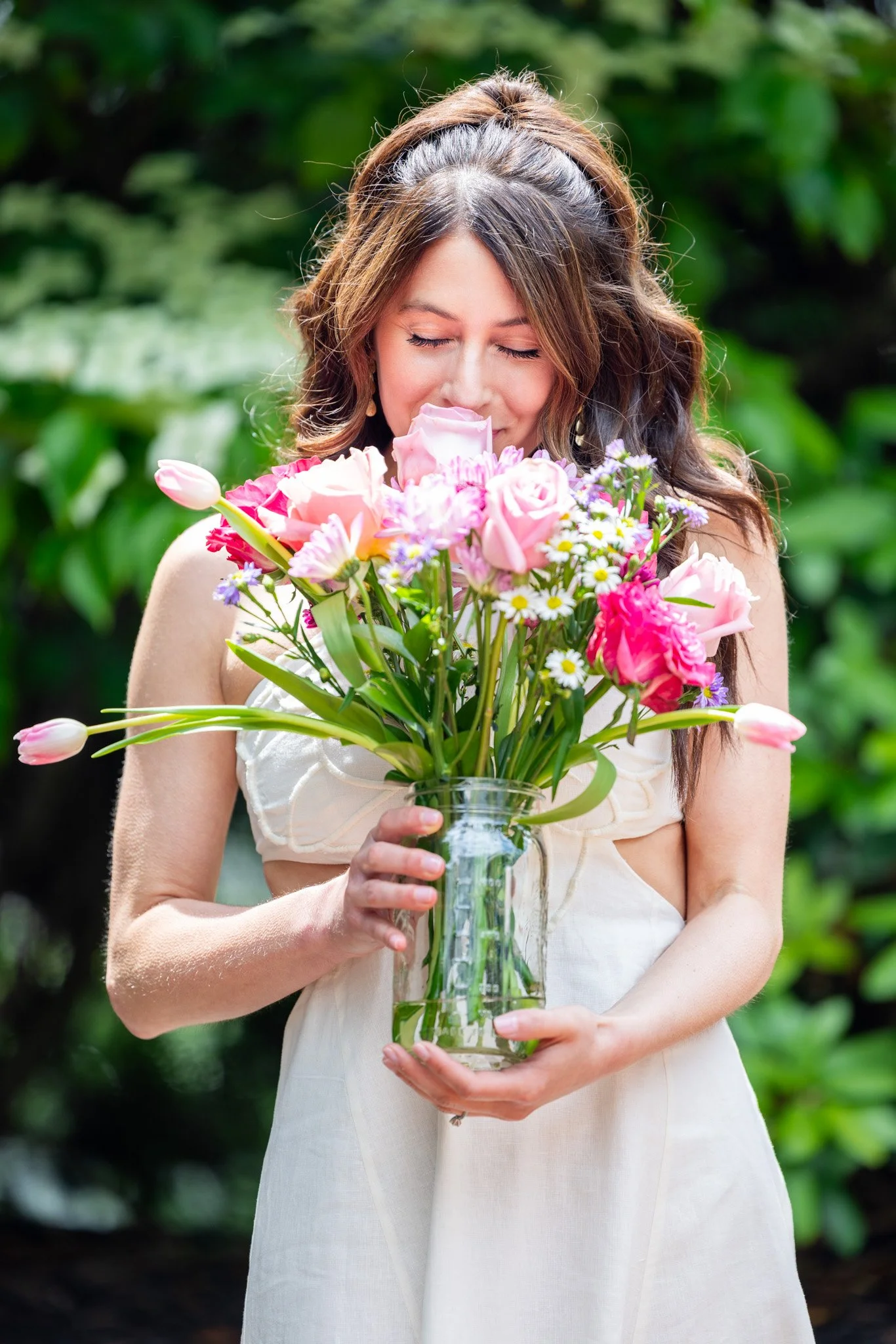 Bride smiling as she smells her pink and white wedding bouquet, captured by David Pierre Studio