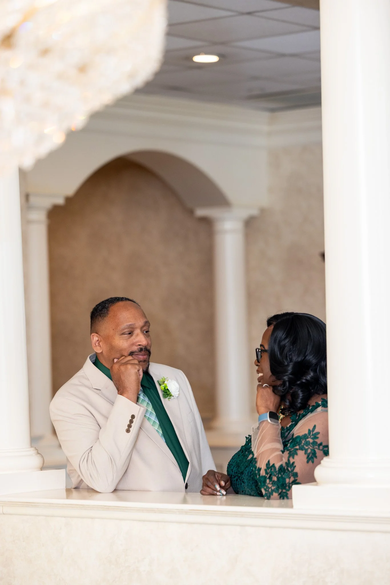 Candid photo of a couple in formal attire talking in an elegant arched hallway at a wedding celebration