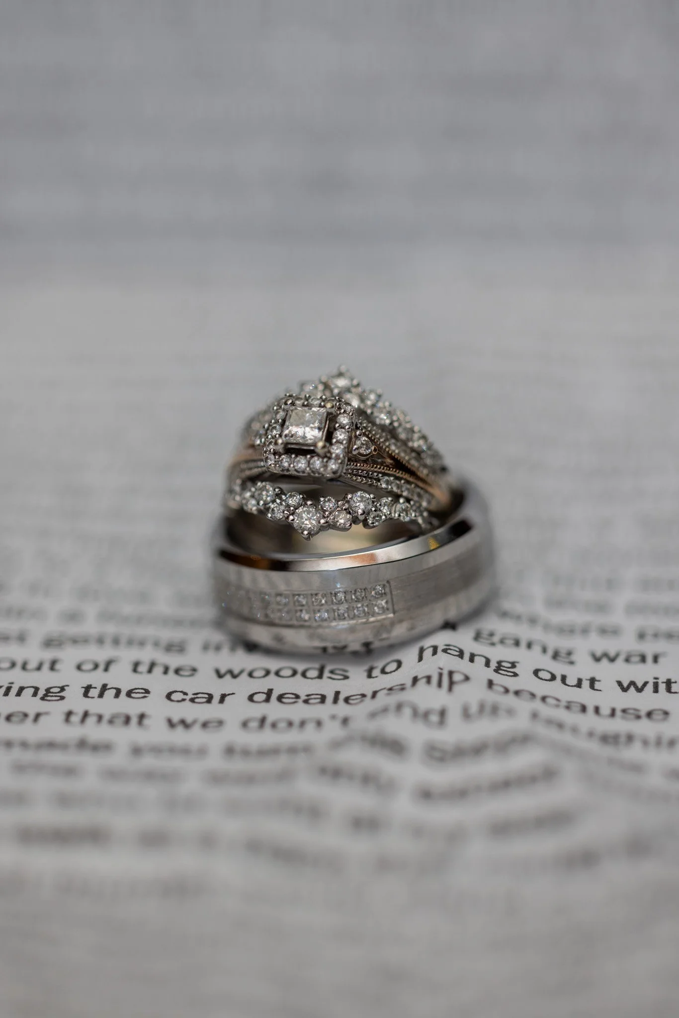 Diamond engagement ring stacked on a wedding band resting on the pages of an open book, wedding ring detail by David Pierre Studio