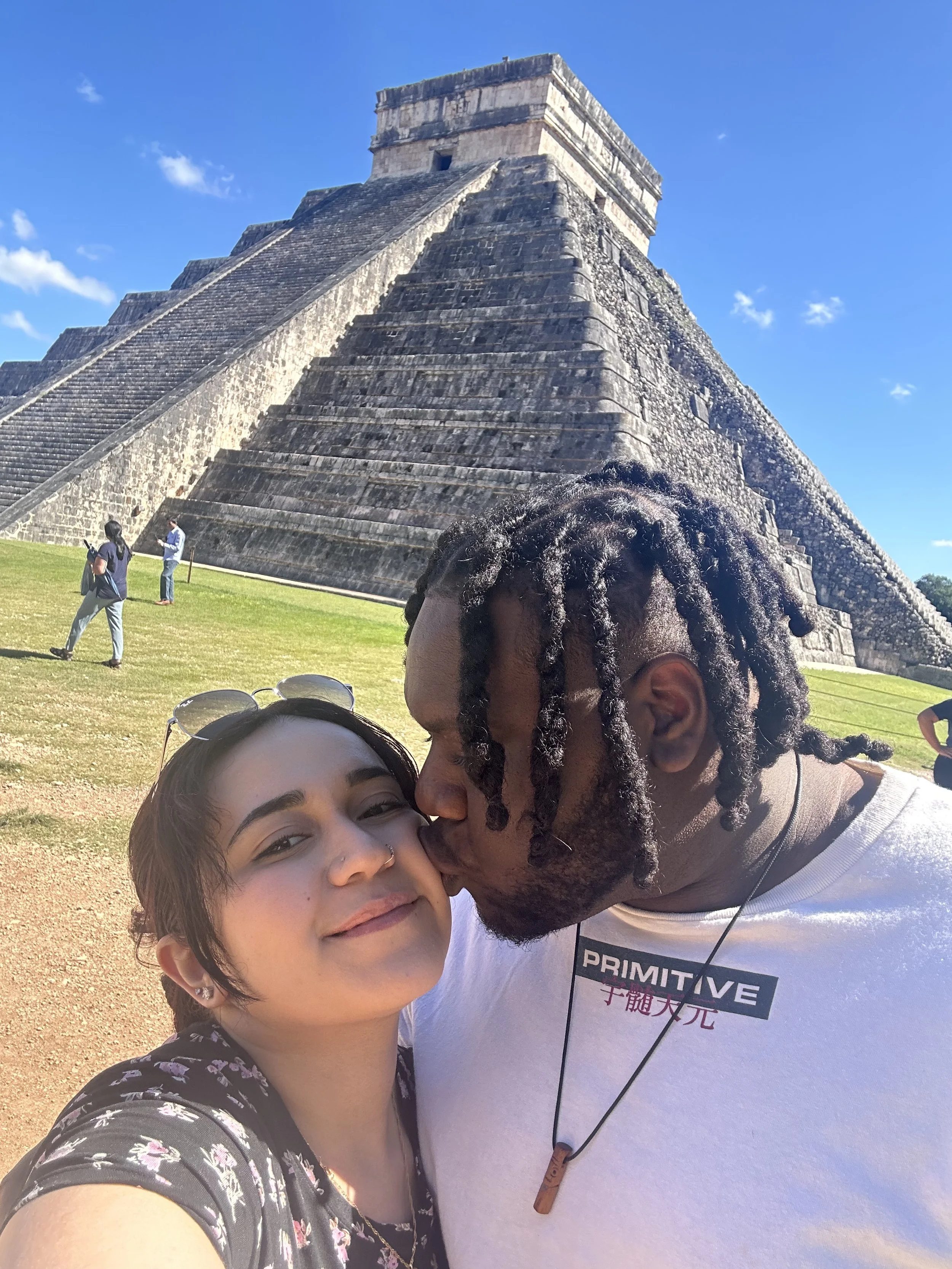 Wedding photographer David and his fiancée smiling together in front of the ancient Chichén Itzá pyramid in Yucatán, Mexico.