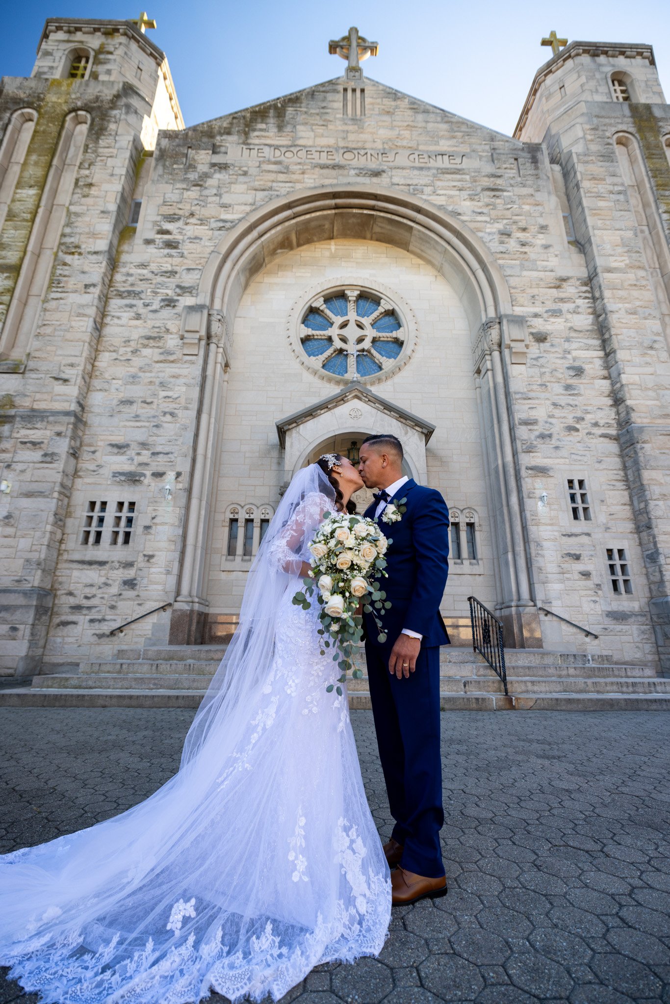 Bride and groom kissing outside a historic stone church on their wedding day, wedding photography by David Pierre Studio