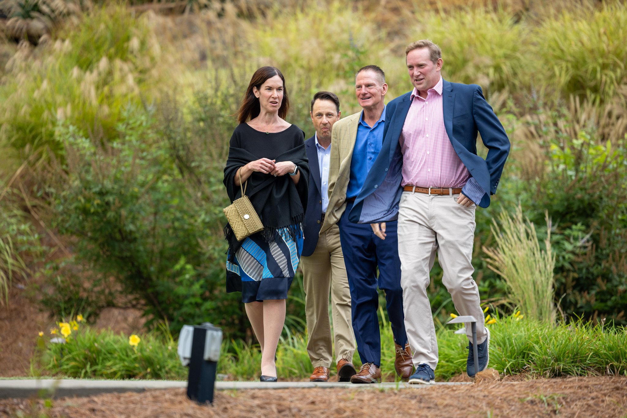 Corporate event attendees walking and talking together along an outdoor garden path, photographed by David Pierre Studio
